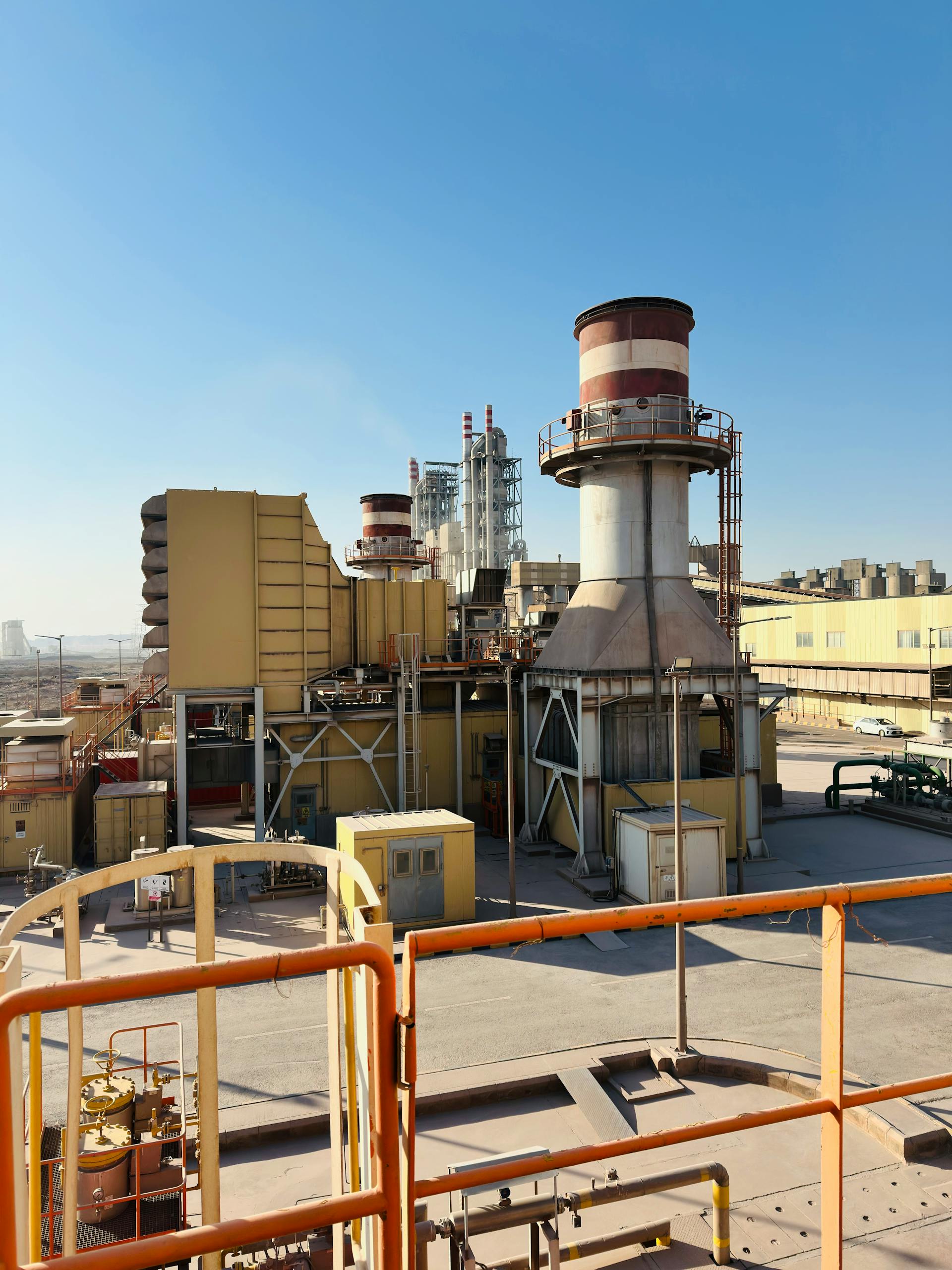 A Saudi Arabian power plant under a clear blue sky, featuring turbines and industrial equipment.